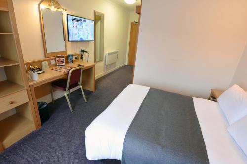 a hotel room with a bed and a desk with a mirror at Royal Oak by Greene King inns in Bromborough