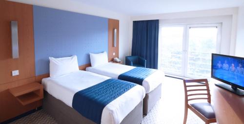 a hotel room with two beds and a television at Ramada London North in Barnet