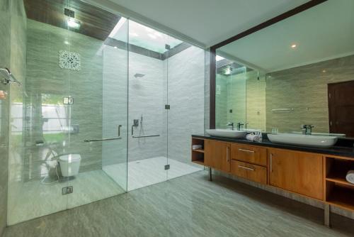 W łazience znajduje się szklana kabina prysznicowa i umywalka. w obiekcie Christina Estate w mieście Seminyak