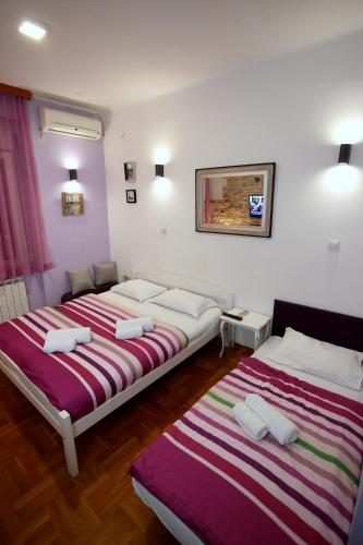 two beds are in a room with purple and white at Apartments Rooms FONTANE TRNJE - FREE PARKING in Zagreb