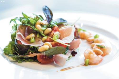 un plato blanco con ensalada con camarones y verduras en Hotel Riu Chiclana - All Inclusive, en Chiclana de la Frontera