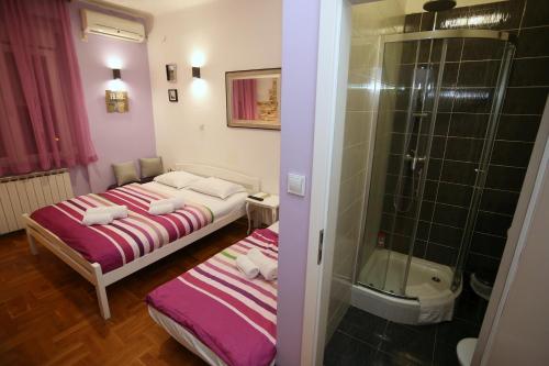 een kleine kamer met 2 bedden en een douche bij Apartments Rooms FONTANE TRNJE in Zagreb