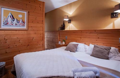 a bedroom with a bed and a lamp on the wall at Hotel Le Monal in Sainte-Foy-Tarentaise