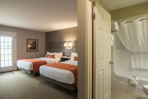 a hotel room with two beds and a bath tub at Amsterdam Inn & Suites Moncton in Moncton