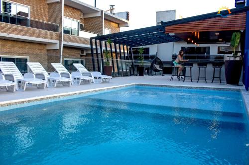 - une piscine avec des chaises et une femme debout à côté d'un bâtiment dans l'établissement Hotel Puesta del Sol, à Encarnación