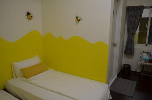a bedroom with a bed with a yellow wall at Kivala Home in Jinfeng