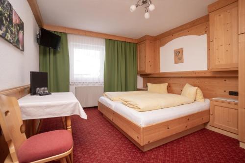 a bedroom with a bed and a table and a desk at Pension Sonnenheim in Sölden