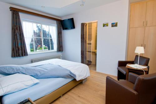 a bedroom with a bed and a window and a chair at De Zilveren Helm in Halen