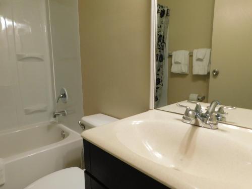 a bathroom with a sink and a toilet and a mirror at APM Inn and Suites in Winchester