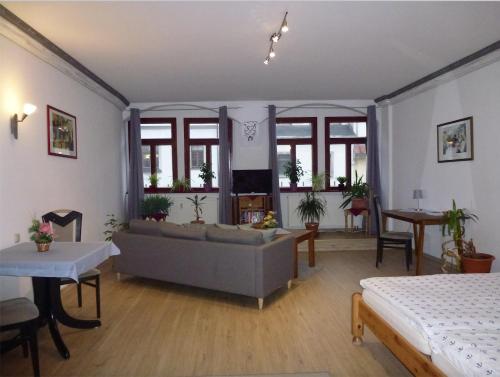ein Wohnzimmer mit einem Sofa, Tischen und Fenstern in der Unterkunft Pension Bergmann-Welp in Freiberg