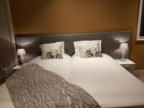 a bedroom with a large white bed with two bicycles on it at De Eenhoorn in Oostburg