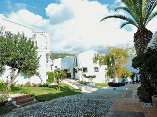 a villa with a palm tree and a walkway at Nerja Villas-Capistrano in Nerja