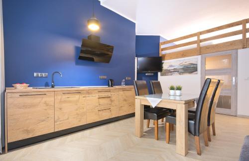 a kitchen with a table and a blue wall at Apartamenty Plażowa 11 in Darłówko