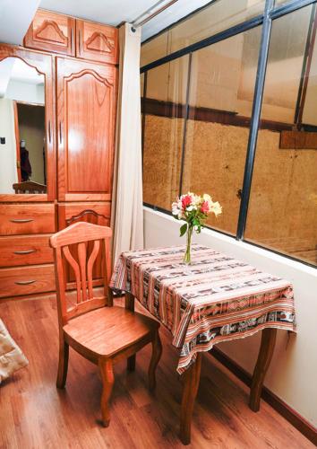 a table and a chair with a vase of flowers on it at Hotel Melanys in Cusco