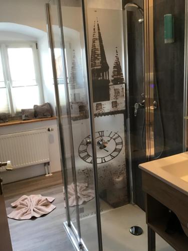 a bathroom with a shower with a clock on the wall at Landhaus Krone in Steinach