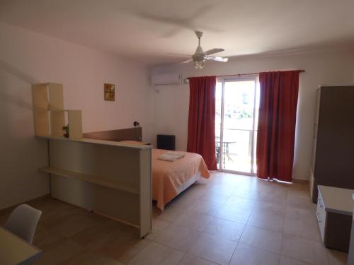 1 dormitorio con 1 cama y una ventana con cortinas rojas en Puerto Termas en Colón