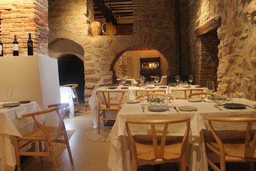 un comedor con mesas blancas y sillas con botellas de vino en Posada Ignatius, en Navarrete