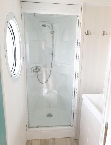 une douche avec une porte vitrée dans une salle de bain dans l'établissement Camping Au Tour de l'Aveyron, à LʼHospitalet-du-Larzac