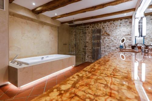 a bath tub in a bathroom with a stone wall at Auberge Saint Walfrid Hôtel Restaurant & Spa in Sarreguemines