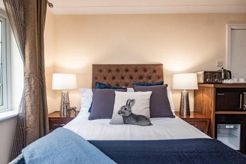 a bedroom with a bed with a rabbit on the pillows at Trivelles Waterhall Country Gatwick Hotel & airport parking in Crawley