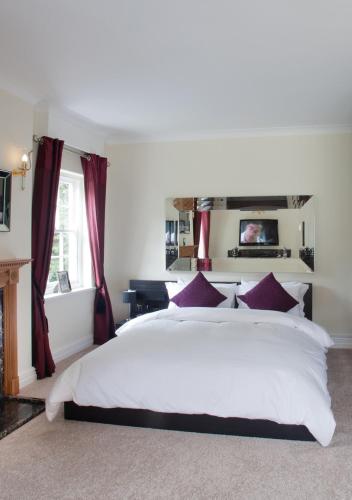 a bedroom with a large white bed with red curtains at Sturmer Hall Hotel and Conference Centre in Haverhill