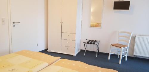 um quarto com uma cama, uma cadeira e um armário em Gästehaus Am Hothertor em Görlitz