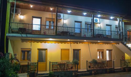 a building with a balcony with tables and chairs at Avgi in Kato Loutraki