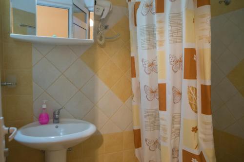 baño con lavabo y cortina de ducha con mariposas en Avgi en Kato Loutraki