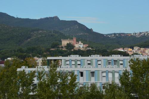 a white building with a mountain in the background at Hotel 170 in Castelldefels