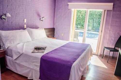 Un dormitorio púrpura con una cama grande y una ventana en Punta del Este San Marcos Eco Hotel, en Punta del Este