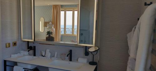 a bathroom with a sink, mirror and bath tub at Splendid Hôtel in Bandol