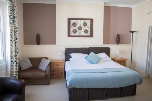 een slaapkamer met een bed en een stoel bij The Sheldon B&B - FREE private parking in Eastbourne