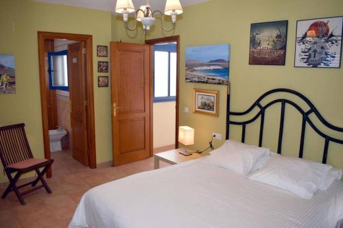 a bedroom with a white bed and a chair at Lanzarote Famara Beach in Famara