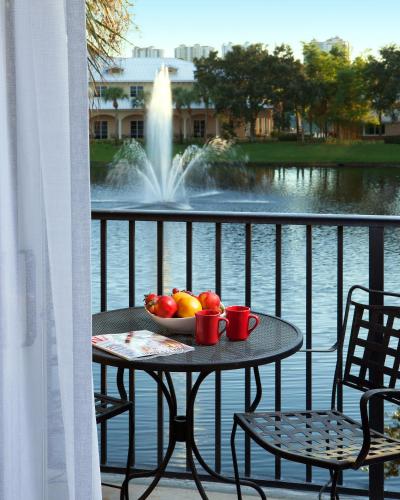 a table with a bowl of fruit on a balcony with a fountain at Inn at Pelican Bay in Naples