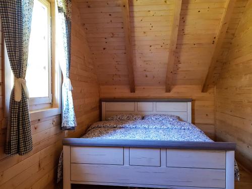 a bed in a wooden cabin with a window at Holiday Home Milica in Kolašin
