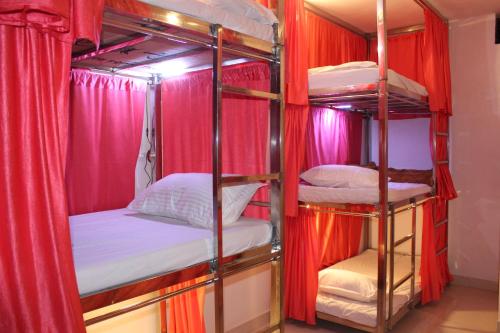 a room with four bunk beds with red curtains at Sunset Backpackers Hostel in Orchha