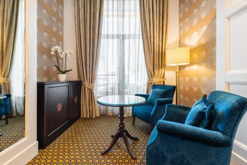 Habitación de hotel con sillas azules, mesa y ventana en Eurostars Gran Hotel La Toja, en Isla de la Toja
