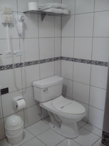 a white bathroom with a toilet and a phone at Llaqta Wasi in Lima