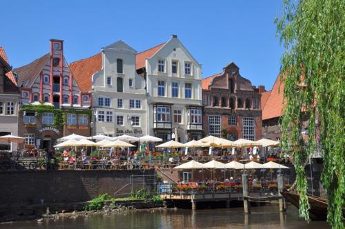 a group of tables with umbrellas next to a river at Hotel Heidpark in Lüneburg