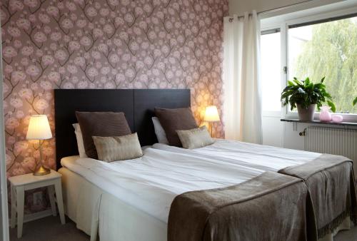 a large white bed in a bedroom with a wall at Riverside Hotel i Ängelholm in Ängelholm