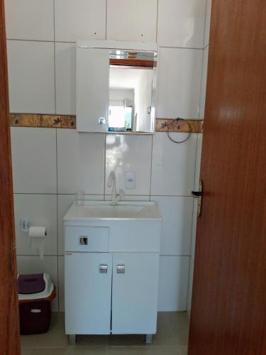 a white bathroom with a sink and a mirror at Apartamento Ilhas Moleques do Sul in Palhoça