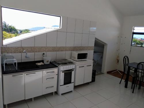 kuchnia z białymi urządzeniami i dużym oknem w obiekcie Apartamento Ilhas Moleques do Sul w mieście Palhoça