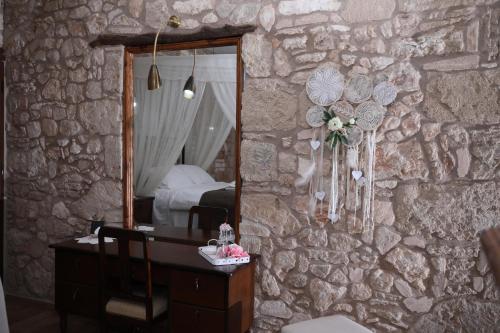 a bedroom with a stone wall with a mirror and a desk at Hanna Koumi Boutique Hotel in Kormakiti