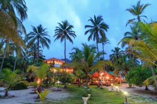 a resort on the beach with palm trees at night at La Mar de Bien in Buritaca