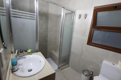 a bathroom with a white sink and a shower at Hanna Koumi Boutique Hotel in Kormakiti