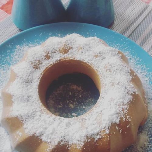 a doughnut with powdered sugar on a blue plate at Agropensiunea Rafila in Pîglişa