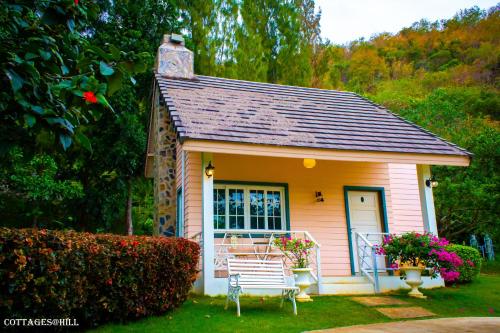 a small pink house with a bench in the yard at Cottages @ Hill Resort in Mu Si