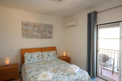 a bedroom with a bed and a sliding glass door at Brisa Mar para 4 com piscina e WiFi in Luz