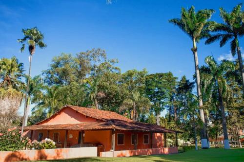 アウト・パライーゾ・デ・ゴイアスにあるA Sua Casa de Campo na Chapadaのヤシの木が背景に広がる小さな家