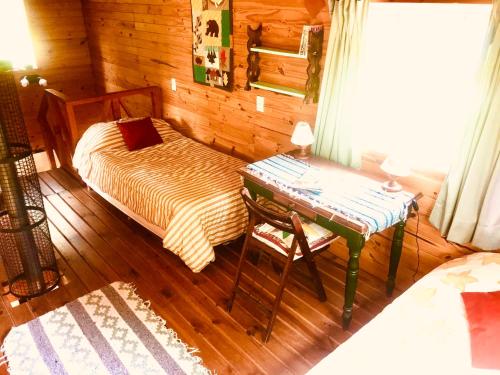 a room with a bed and a table in a cabin at Cabaña de Montaña in San Carlos de Bariloche